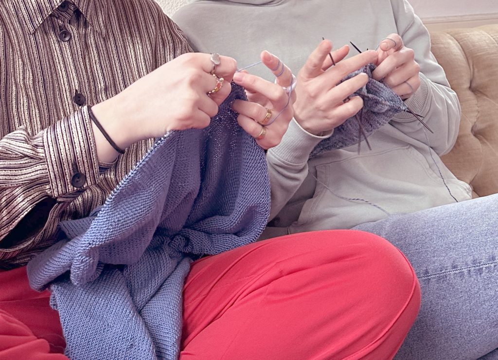 zwei Menschen sitzen nah zusammen und stricken